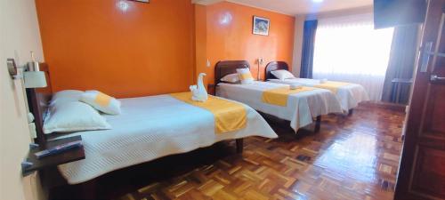 two beds in a room with orange walls at Hotel Express in La Paz