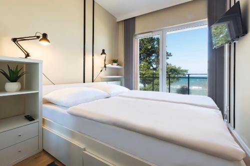 Un dormitorio con dos camas blancas y una ventana. en VacationClub - Let’s Sea Baltic Park C83, en Gąski