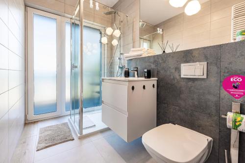 a bathroom with a white toilet and a shower at VacationClub - Let’s Sea Baltic Park C83 in Gąski