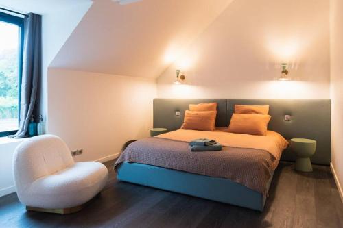 - une chambre avec un lit et une chaise blanche dans l'établissement Magnifique ferme rénovée, à La Landec