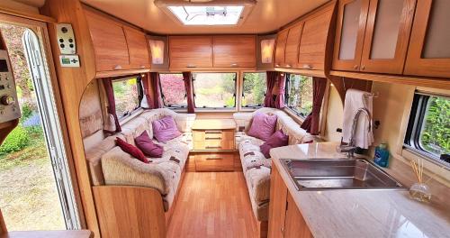 ein Interieur aus einem Wohnwagen mit Sofas und einem Waschbecken in der Unterkunft Park Farm Holidays Glamping in Lyndhurst