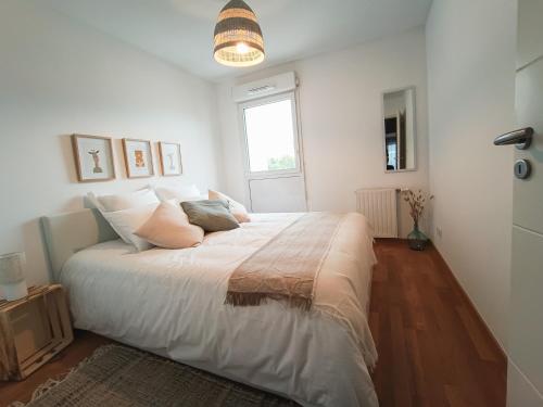 Schlafzimmer mit einem großen weißen Bett und einem Fenster in der Unterkunft T3 Lumineux - Berges de la Garonne - Parking in Toulouse