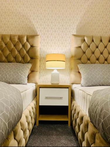 a bedroom with two beds and a table with a lamp at Glasgow City Centre Flat with River Views and Parking in Glasgow