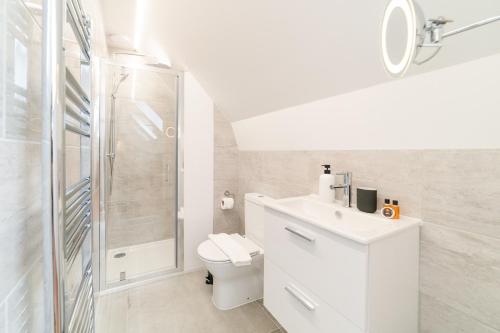 a white bathroom with a toilet and a shower at Cosy Two Bedroom Flat in London near Westfield in London