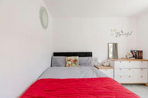 London Home With A Beautiful View في Upper Norwood: غرفة نوم بسرير كبير مع بطانية حمراء