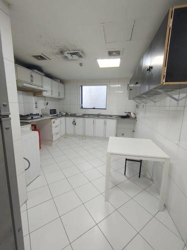 a white kitchen with a table in the middle of it at Second Home in Dubai