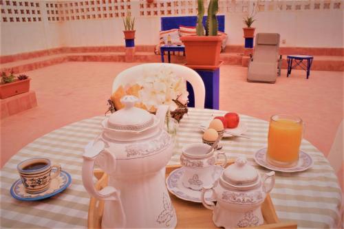un tavolo con bollitore per tè, tazze e succo di frutta di Asunfou : Appartement d'apaisement a Mirleft