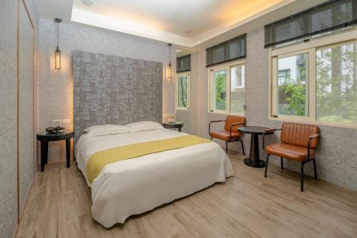 a bedroom with a large bed and two chairs at 沐-湯宿溫泉行旅 in Jiaoxi