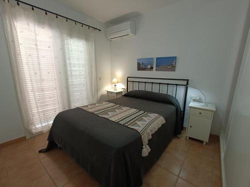 um quarto com uma cama e uma janela com persianas em apartamento en el parque natural del cabo de gata em Almería