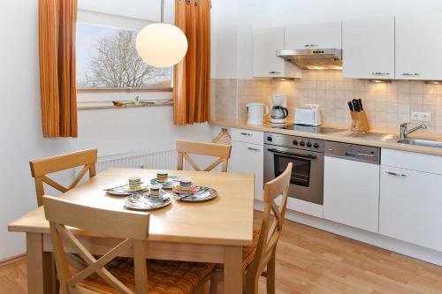 a kitchen with a wooden table with chairs and a table and a sink at Gutshaus von Bülow - 19-02 in Kägsdorf