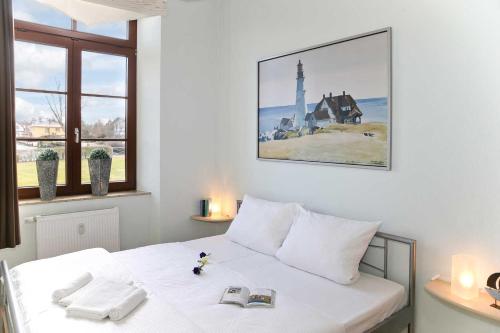 Un dormitorio con una cama blanca con una foto en la pared en Gutshaus von Bülow - 19-05, en Kägsdorf