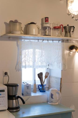 a kitchen counter with a window with a curtain at Blue Bay Heliolithos in Parikia