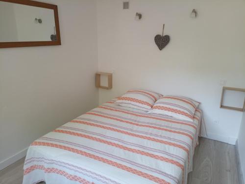 uma cama num quarto branco com um cobertor listrado em Gîte l'Olivianne em Crépy-en-Valois