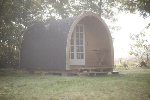 a small house with a gambrel roof in a field at Campingpod back to basic in Tønder