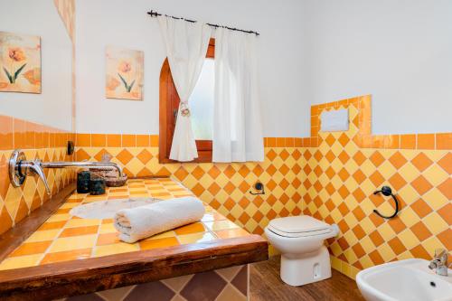 a yellow tiled bathroom with a toilet and a sink at Suite Harmony in Loiri