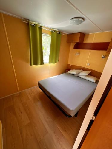 une chambre avec un lit dans une petite pièce avec des rideaux verts dans l'établissement Camping parc les 7 fonts, à Agde