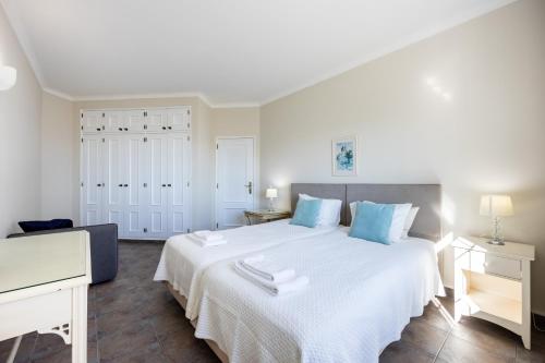 een slaapkamer met een groot wit bed met blauwe kussens bij CoolHouses Algarve Luz, 1 bed penthouse flat w/ sea views. Fiji 11 in Luz