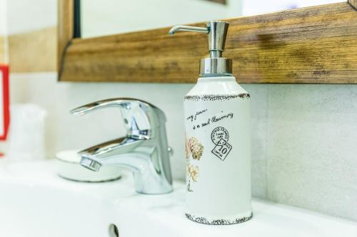 a soap bottle sitting on a sink next to a faucet at Casa Novecento "Rooms & apartments" in Feltre