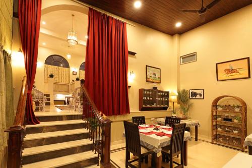 a dining room with a table and a red curtain at The Cavalry - Abhay Niwas in Udaipur