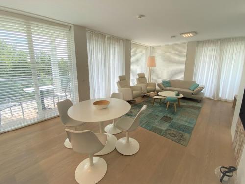 a living room with a couch and a table and chairs at Badhuis Dunes, Boulevard de Wielingen 2 in Cadzand