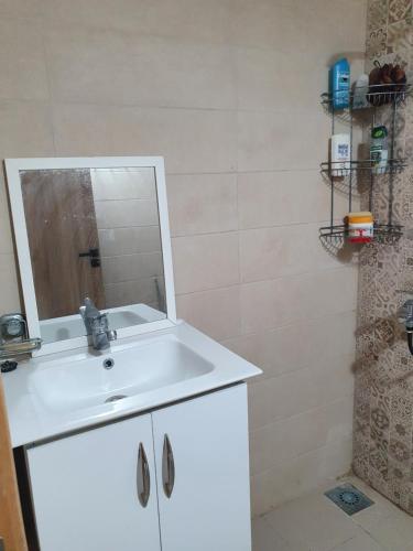 a bathroom with a white sink and a mirror at Appart calme, neuf à 5mn de la plage SAADIA in Saidia 