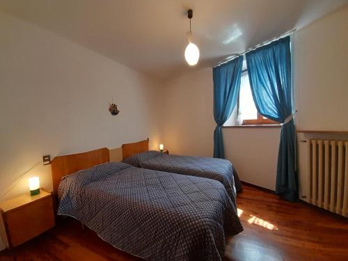 ブレンゾーネにあるDomus Antiquaのベッドルーム1室(ベッド2台、青いカーテン付きの窓付)