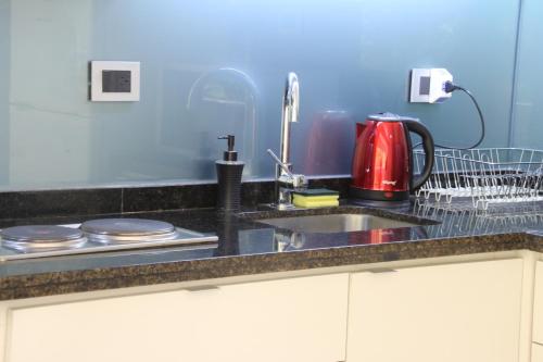 a kitchen counter with a sink and a red tea kettle at Guemes Apartment in San Juan