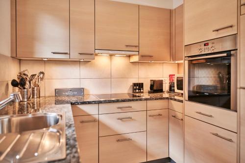 a kitchen with wooden cabinets and a sink at Apartment Mountain View, Luxury, Spacious with best Views in Lauterbrunnen