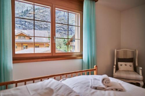 a bedroom with a bed and a window and a chair at Apartment Mountain View, Luxury, Spacious with best Views in Lauterbrunnen
