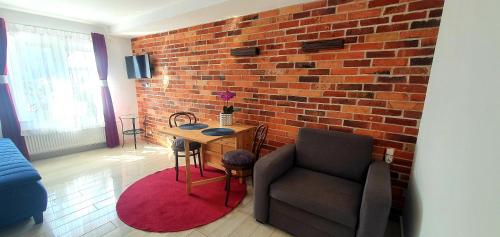 a living room with a chair and a brick wall at Apartamenty Orchidea Łeba in Łeba