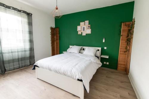 appart de charme a 2 pas du centre de Montbrison في مونتبريسون: غرفة نوم بحائط أخضر وسرير أبيض