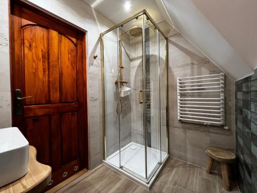 a shower with a glass door in a bathroom at POD ROŻKAMI in Cisna