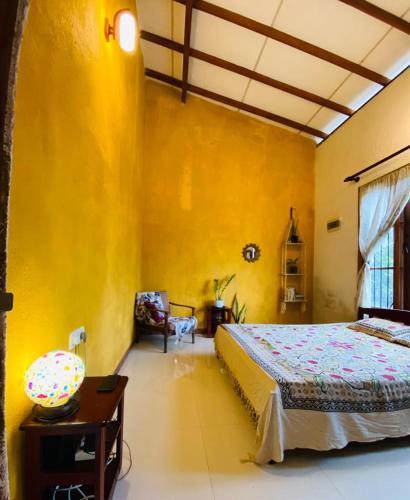 a bedroom with a bed and a yellow wall at Pearl's Homestay Matale in Matale