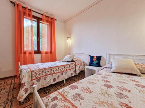 2 camas en una habitación con cortinas naranjas y ventana en Villa Mirella Trilocale, en Capoliveri