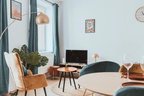 a living room with a table and chairs and a tv at JUPITER - Un logement neuf et de qualité in Saint-Étienne