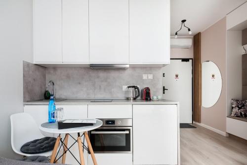 a kitchen with white cabinets and a table in a room at Central Apartments by Bed&Bath in Kraków