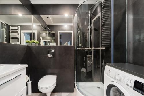 a bathroom with a toilet and a sink and a washing machine at Central Apartments by Bed&Bath in Kraków