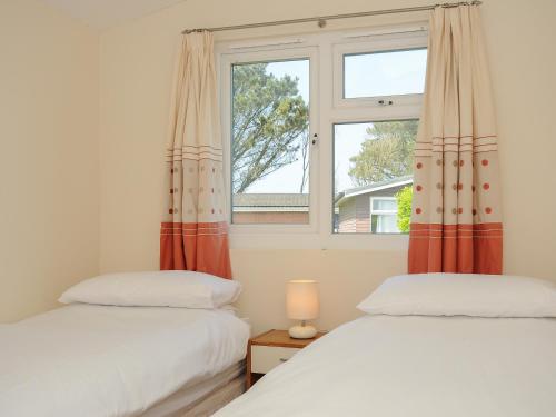 two beds in a room with a window at Little Trebah in St Merryn