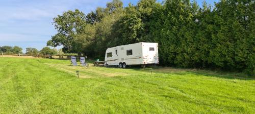 a white trailer parked in a field next to a tree at Park Farm Holidays Glamping in Lyndhurst