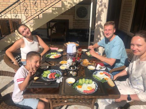 een groep mensen die rond een tafel zitten met eten bij OLD CITY guest house in Samarkand