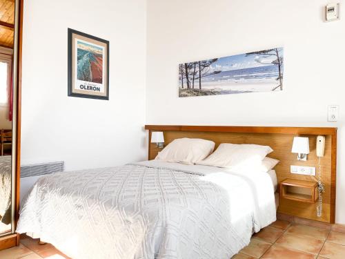 Un dormitorio con una cama blanca y una foto en la pared en Hôtel L'Hermitage en Saint-Georges-dʼOléron