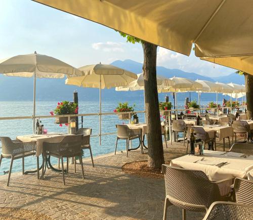 een openluchtrestaurant met tafels en stoelen en de oceaan bij Hotel Pai in Torri del Benaco