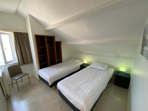 um quarto de hotel com duas camas e uma cadeira em Karen - 1st floor, Duinlaan 5b em Cadzand