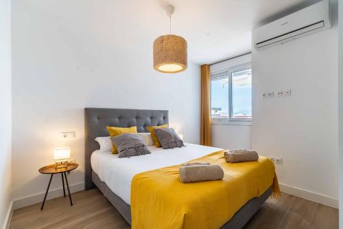 a bedroom with a large bed with a yellow blanket at Sur Suites Palmeras 9 in Fuengirola