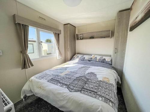 a bedroom with a bed in a room with a window at Gorgeous Caravan With Decking In Breydon Water Holiday Park, Ref 10081b in Belton