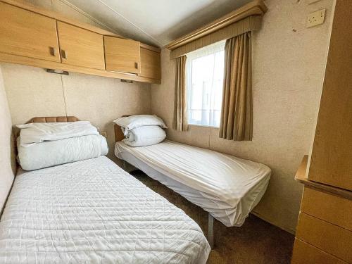 a small room with two beds and a window at Lovely 6 Berth Caravan With Decking At California Cliffs In Scratby Ref 50048l in Great Yarmouth