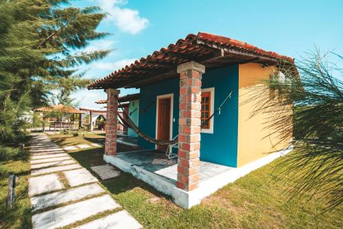 a small blue and yellow house with a palm tree at Vila Capininga Ecopousada in Santo Amaro