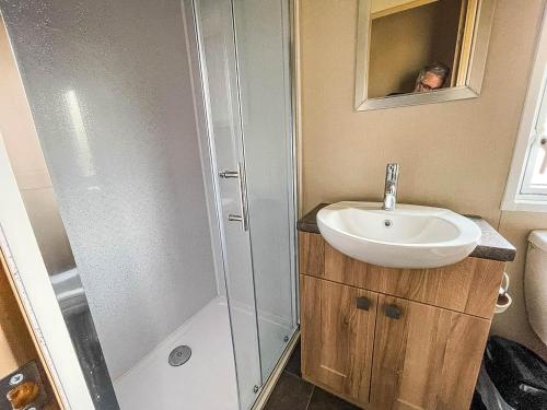 a bathroom with a sink and a shower at Beautiful Caravan With Sea Views At California Cliffs In Scratby Ref 50010oc in Great Yarmouth