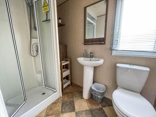 a bathroom with a toilet and a shower and a sink at Lovely Caravan With Decking And Free Wifi In Lowestoft Ref 12106b in Lowestoft