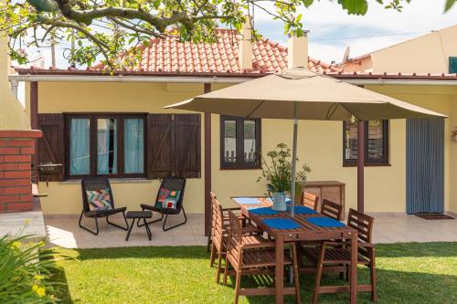 a table and chairs under an umbrella in a yard at Casa da Varzinha in A dos Cunhados